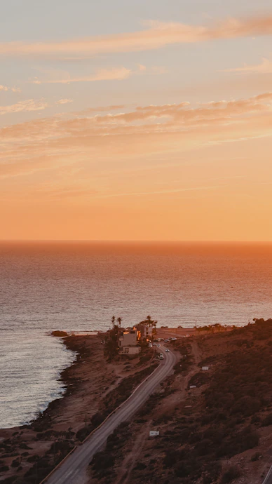 an airplane is flying over the ocean at sunset