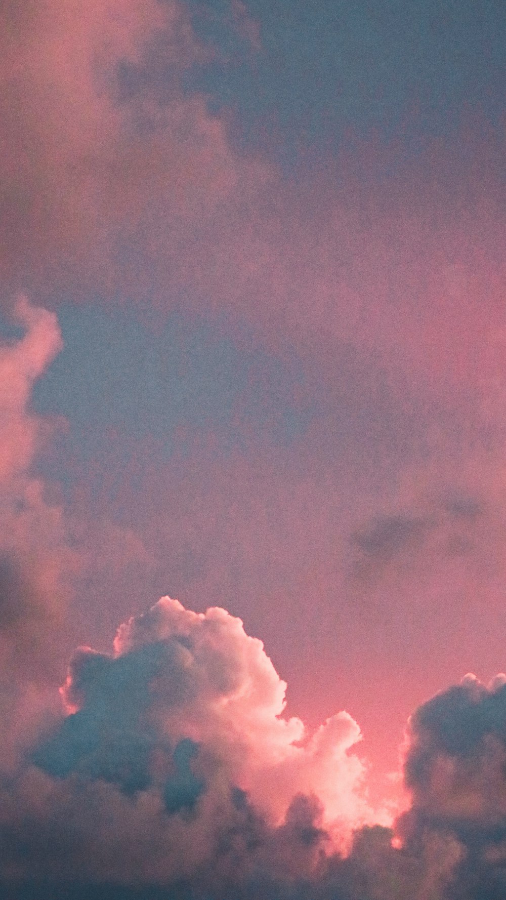 a plane flying through a cloudy sky at sunset