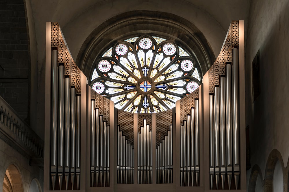 a pipe organ in a church with a large stained glass window