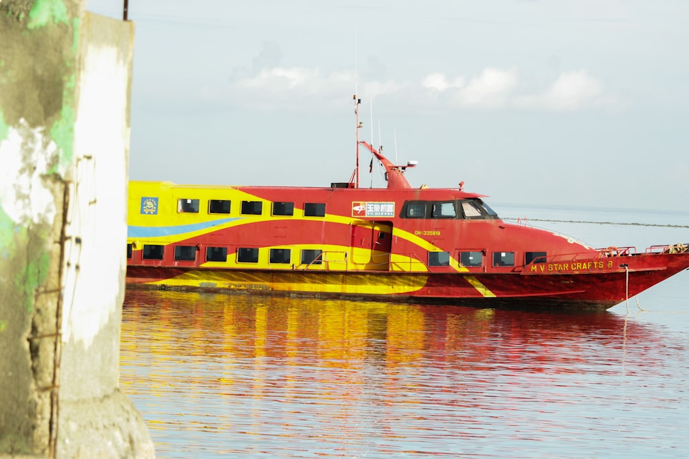 a red and yellow boat floating on top of a body of water
