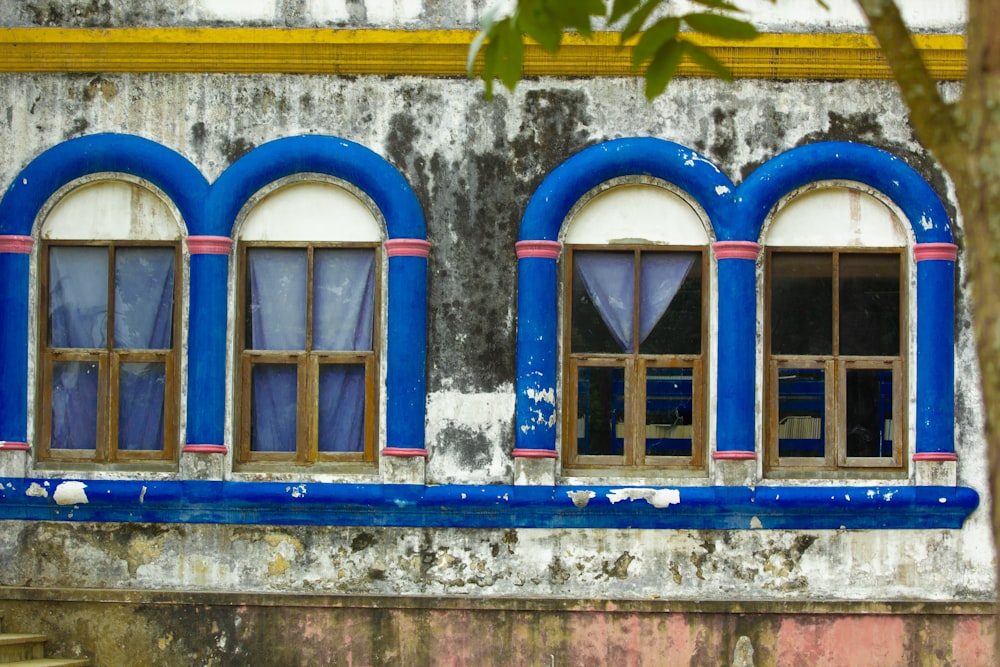 an old building with blue windows and a wooden bench