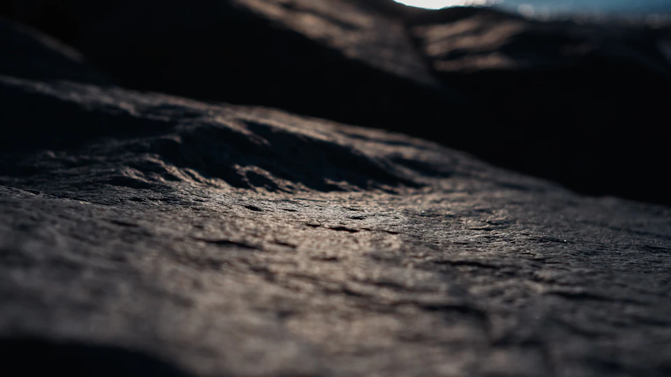 Close-up view of a rocky cliff face with dark, textured surface from below