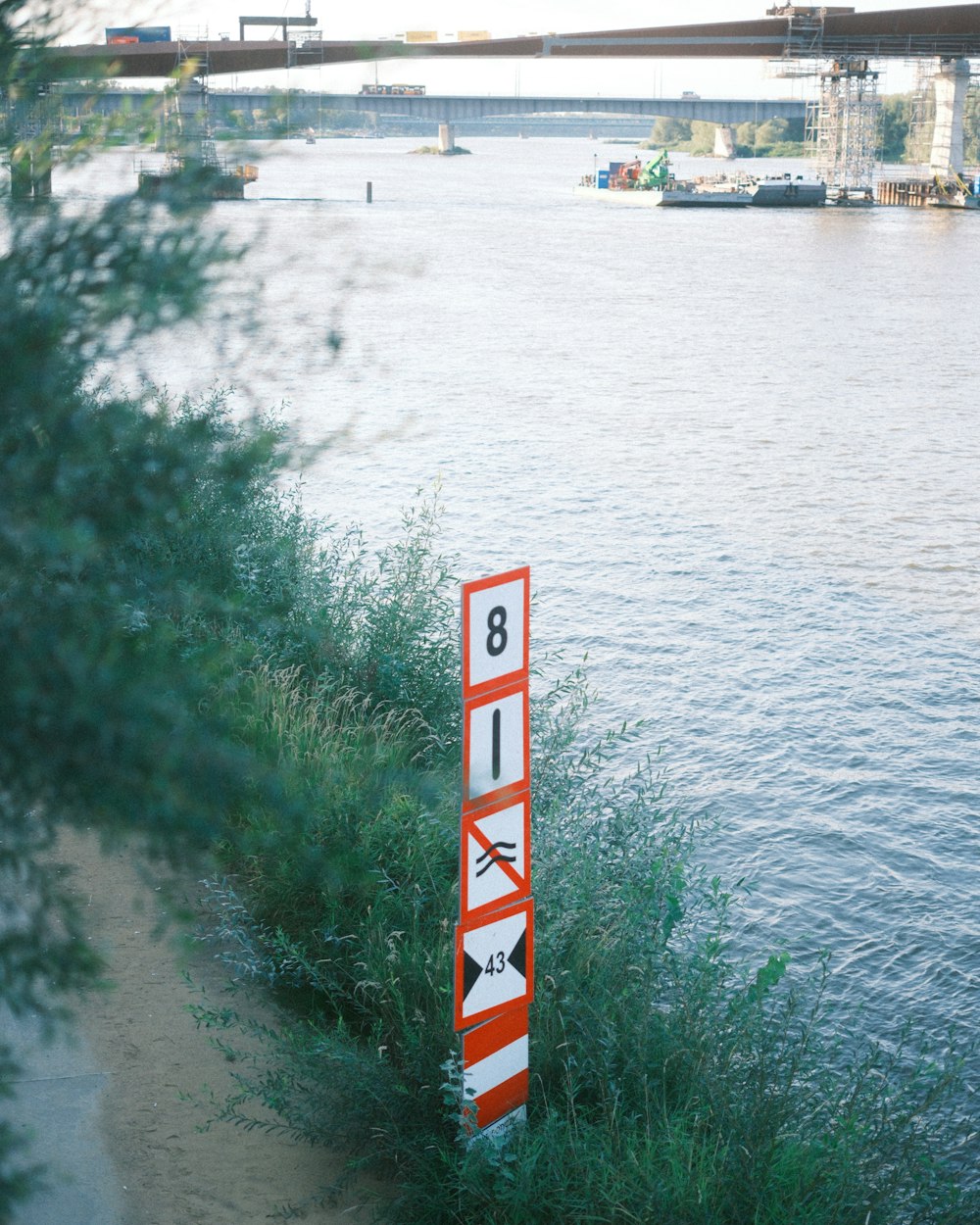 a red and white sign sitting on the side of a river