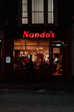 a store front with a neon sign that reads nando's