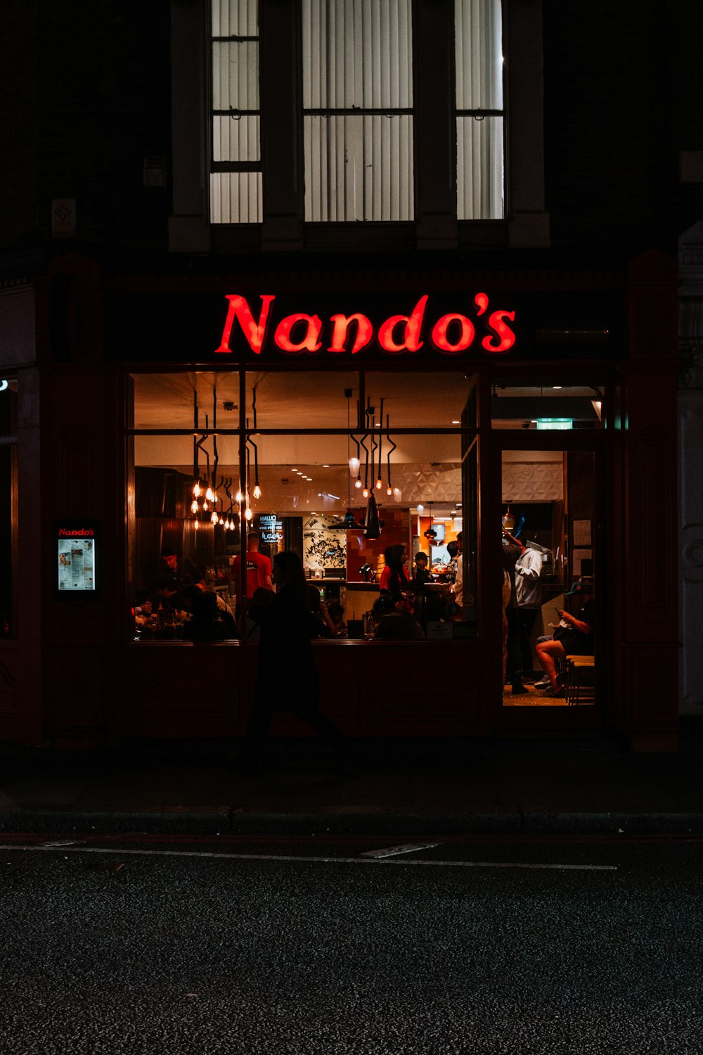 Un frente de tienda con un letrero de neón que dice Nando's