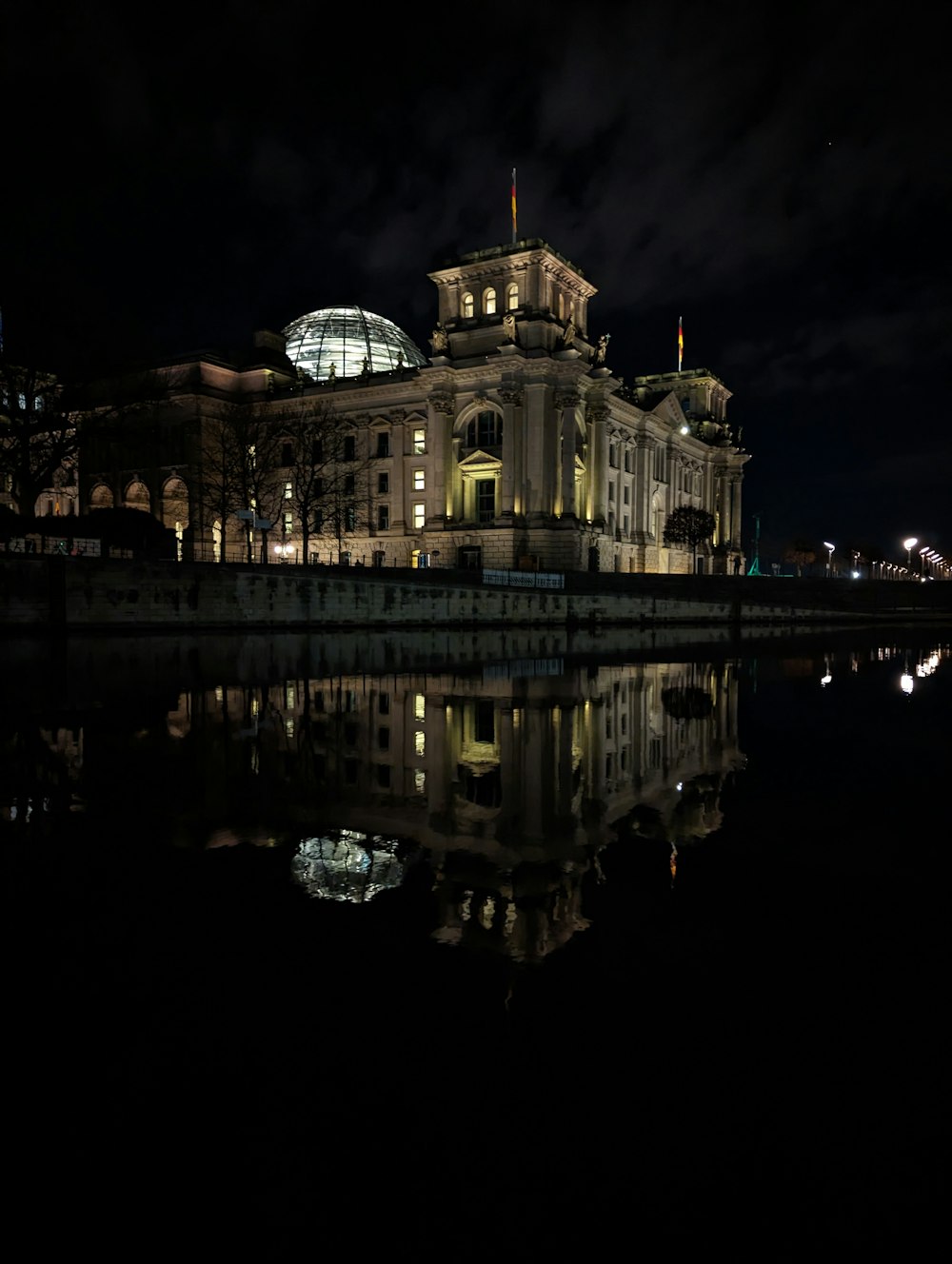 a building lit up at night next to a body of water