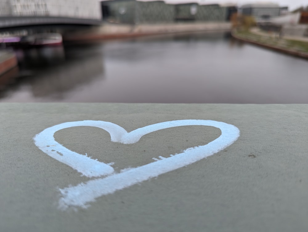 a heart drawn on the side of a building next to a river