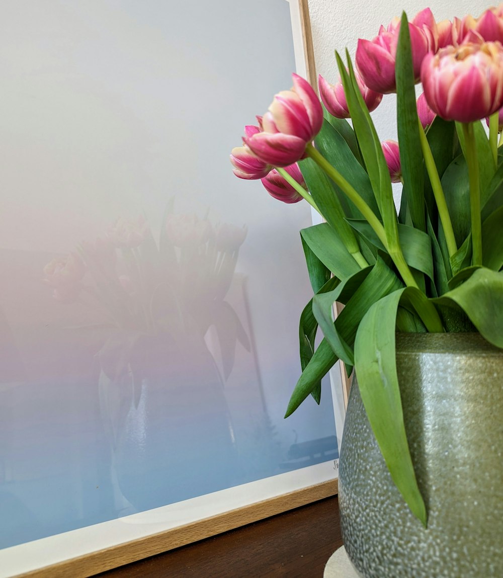a vase filled with pink flowers next to a picture