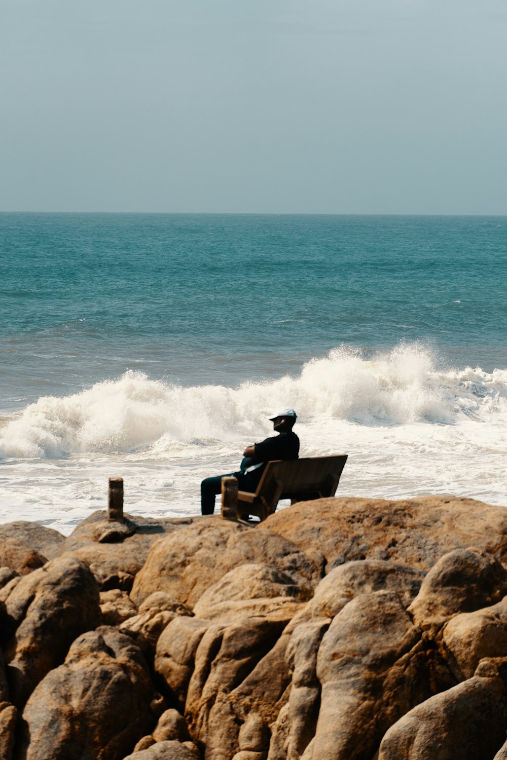 um homem sentado em cima de um banco ao lado do oceano