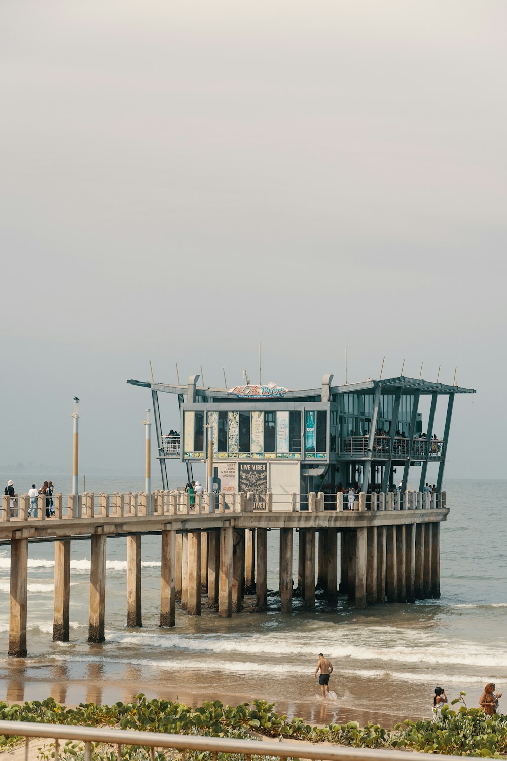 a pier on the beach with people standing on it
