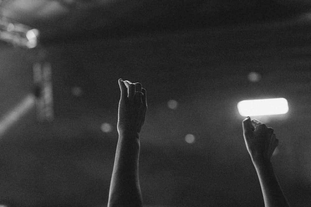 a black and white photo of a person raising their hands