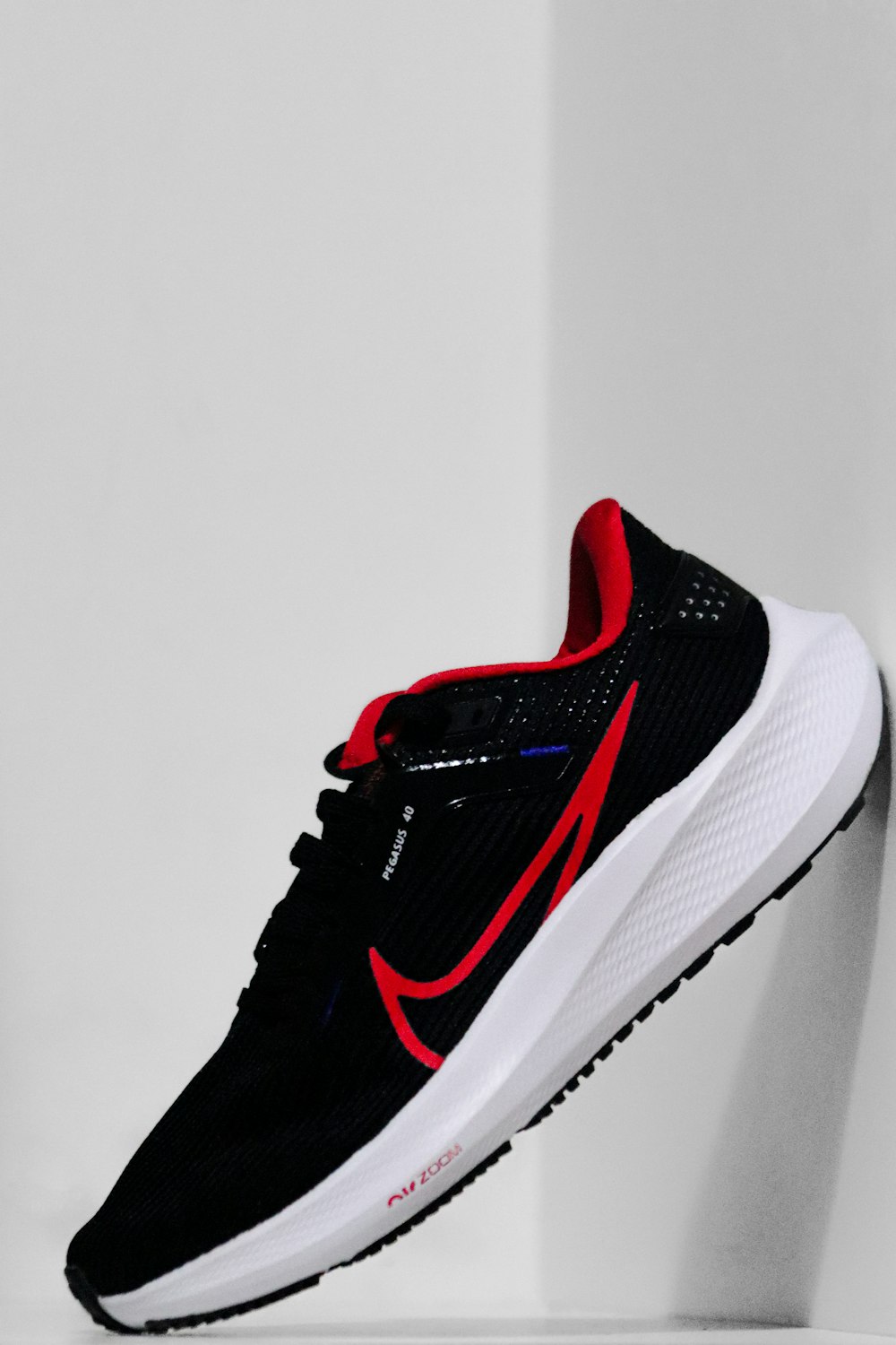 a pair of black and red sneakers hanging on a wall