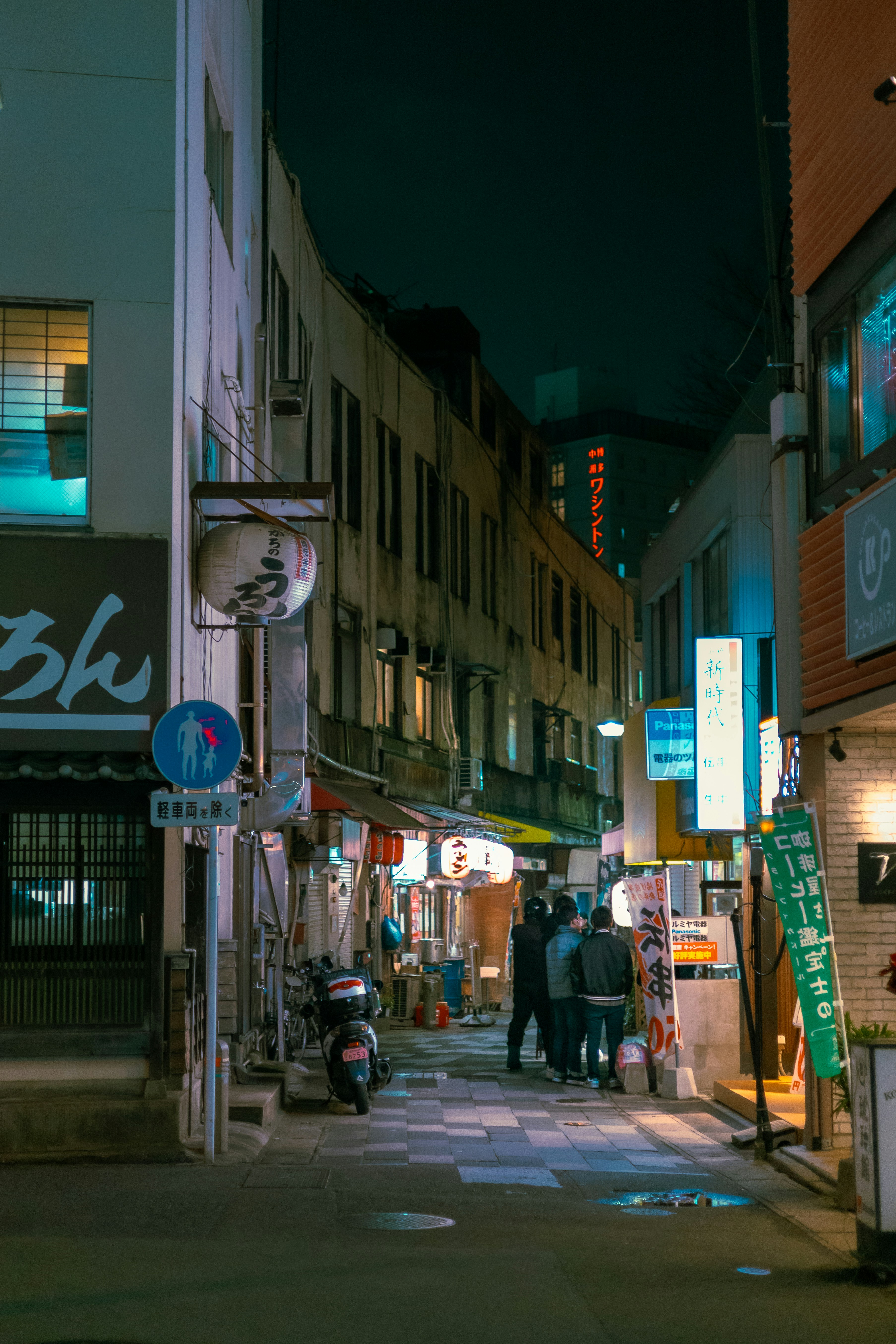a couple of people walking down a street next to tall buildings