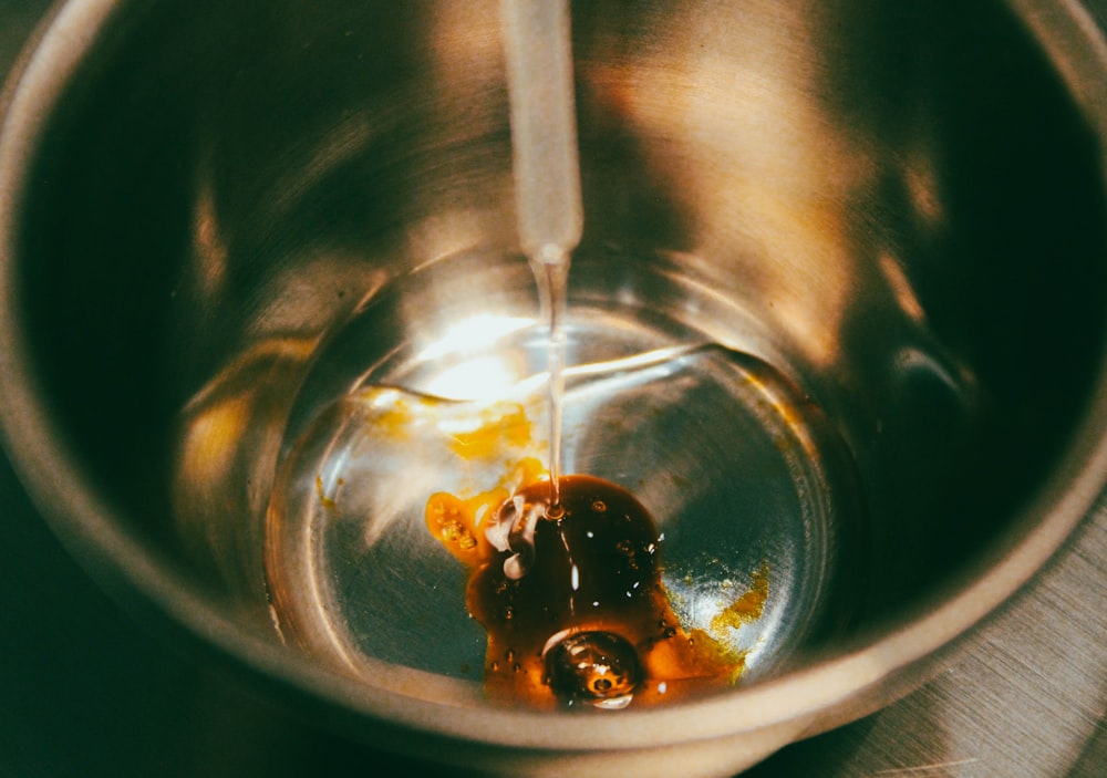 a metal bowl filled with liquid on top of a table