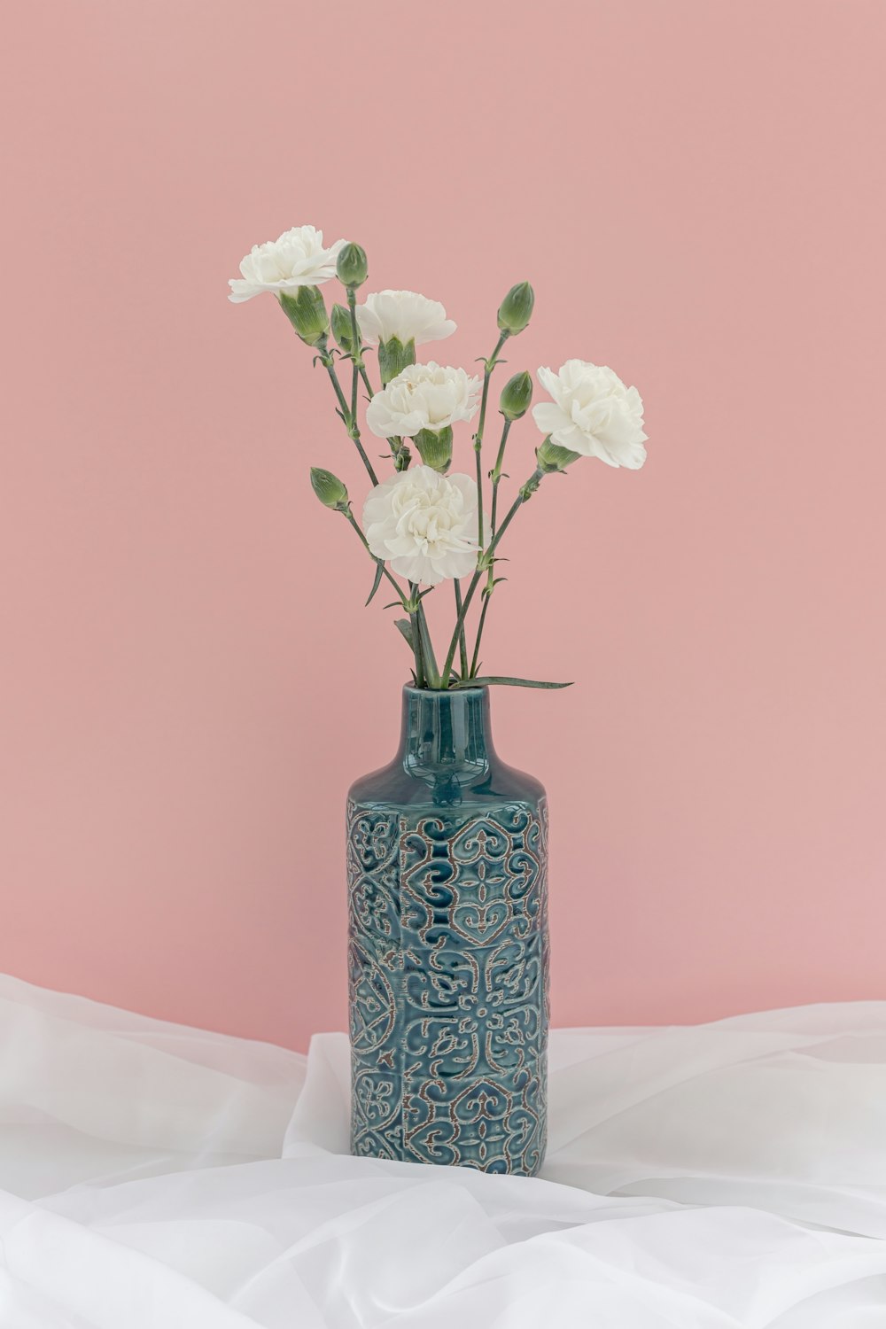 a blue vase filled with white flowers on top of a bed
