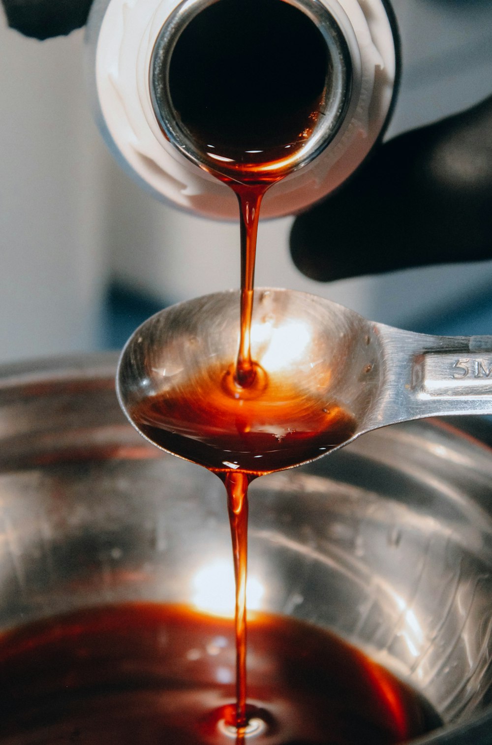 a spoon full of sauce being poured into a bowl
