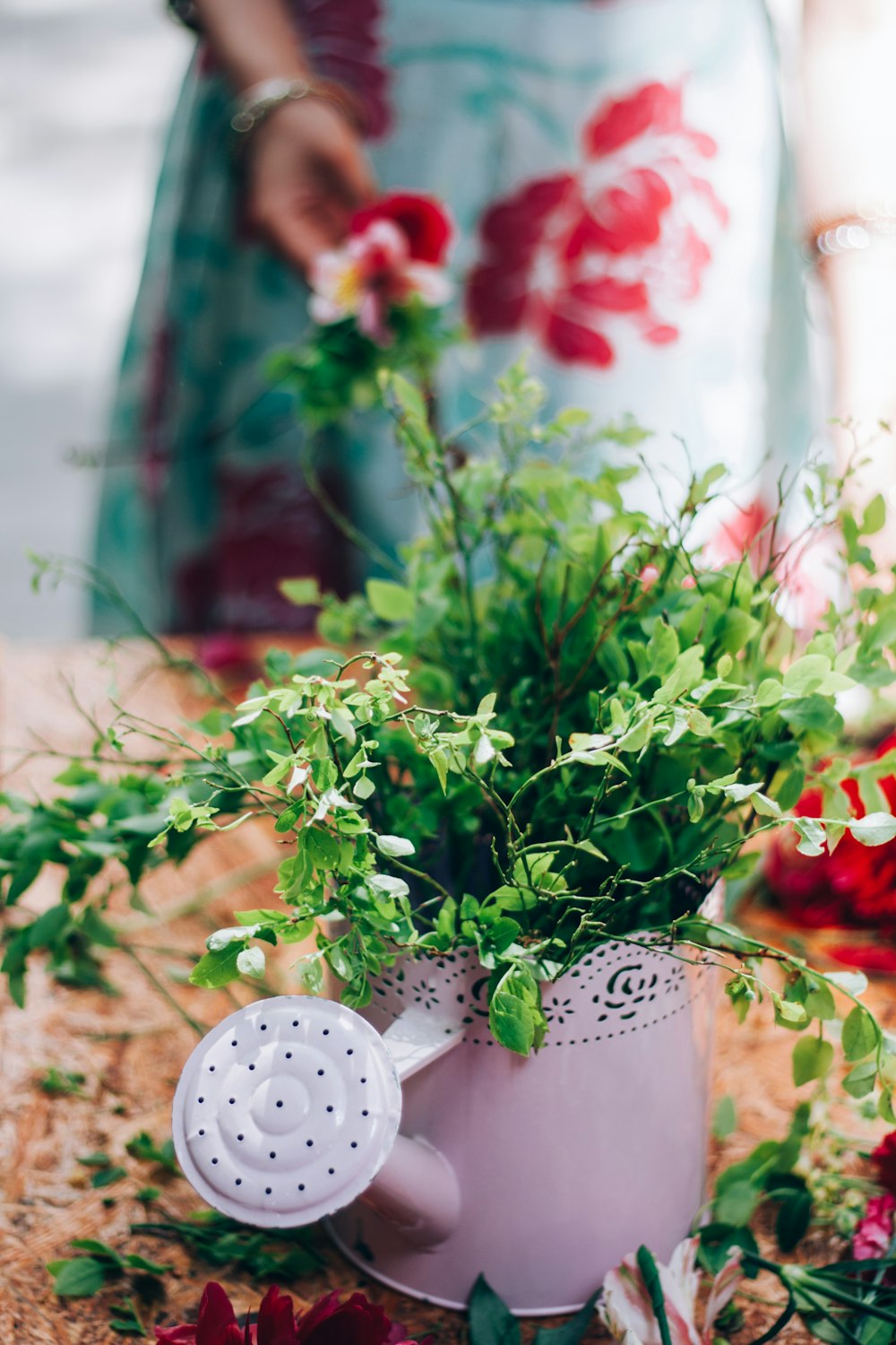 a watering can filled with plants on a table