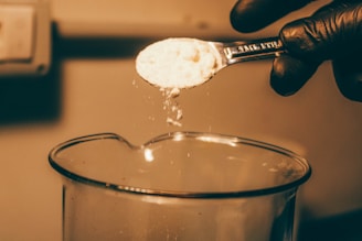 a person spooning sugar into a glass of water