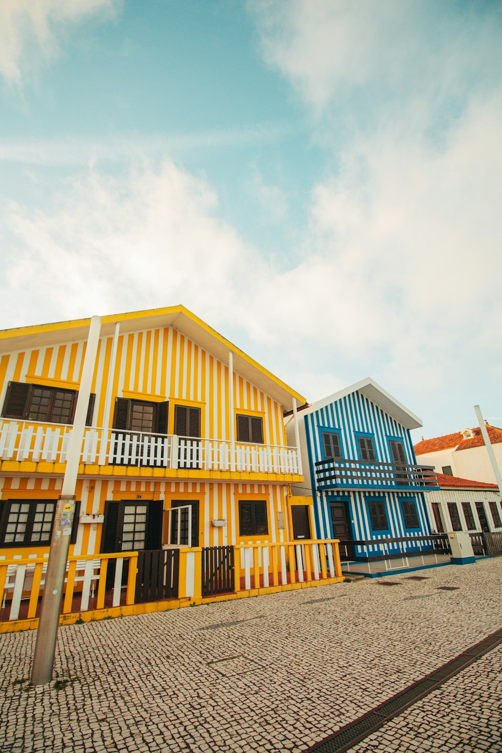 a row of multi - colored houses on a cobblestone street