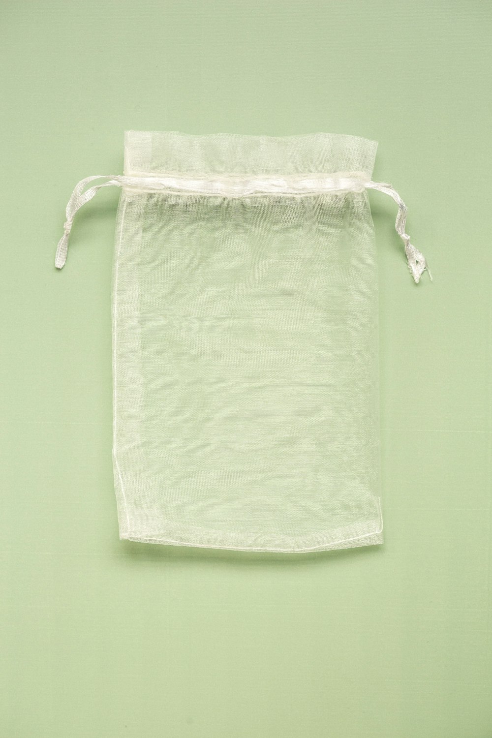 a white linen bag hanging on a green wall