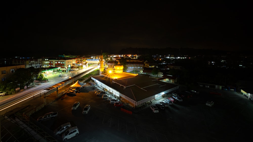a night time view of a parking lot with a clock tower in the background