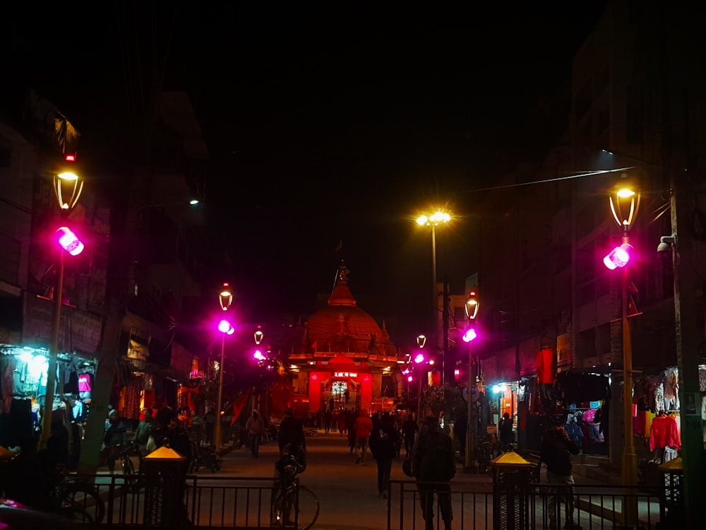 a group of people walking down a street at night