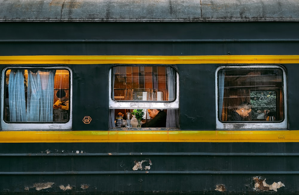 a yellow and black train car with three windows