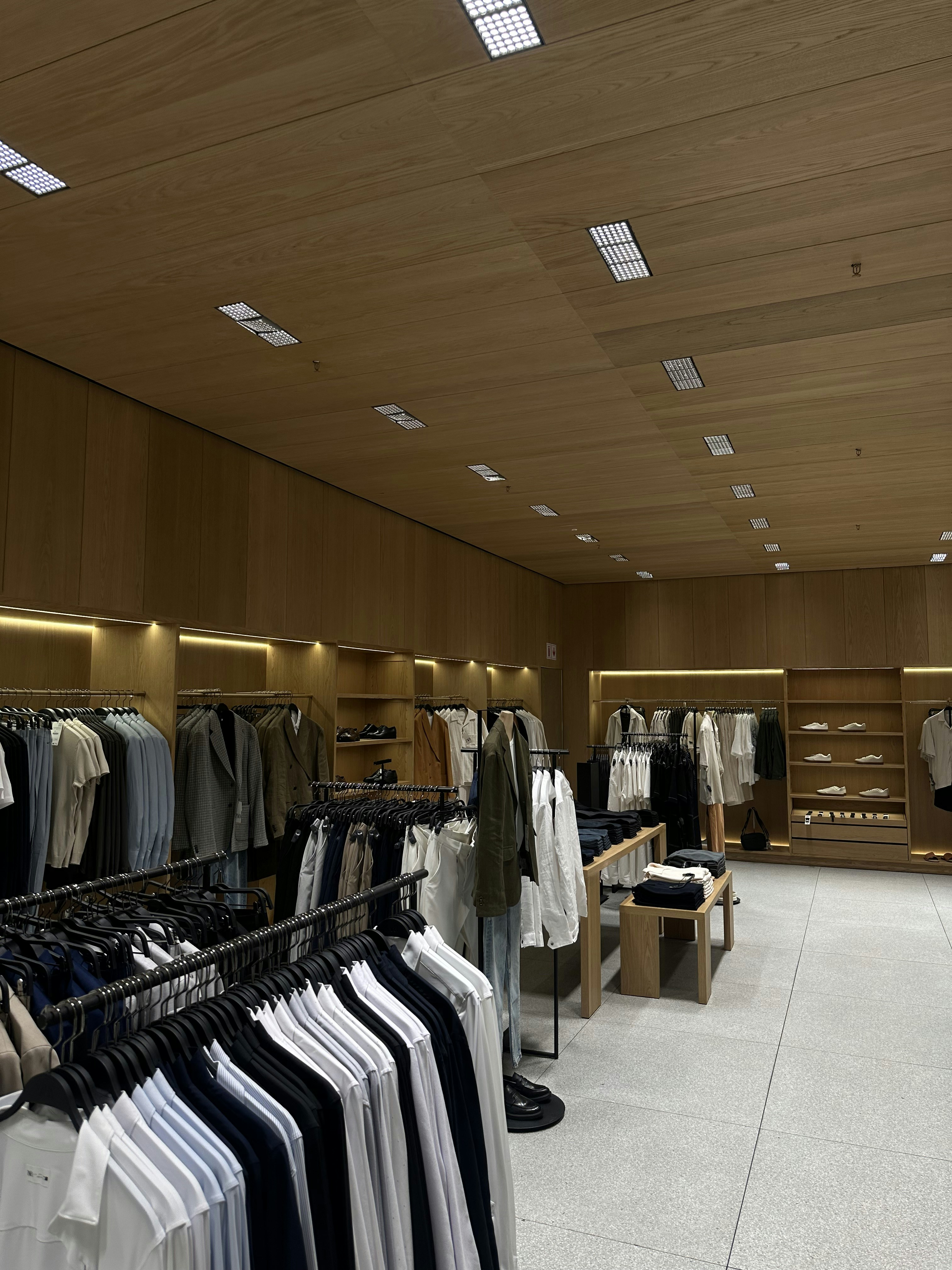 Bright retail clothing store with well-lit white walls and organized clothing displays