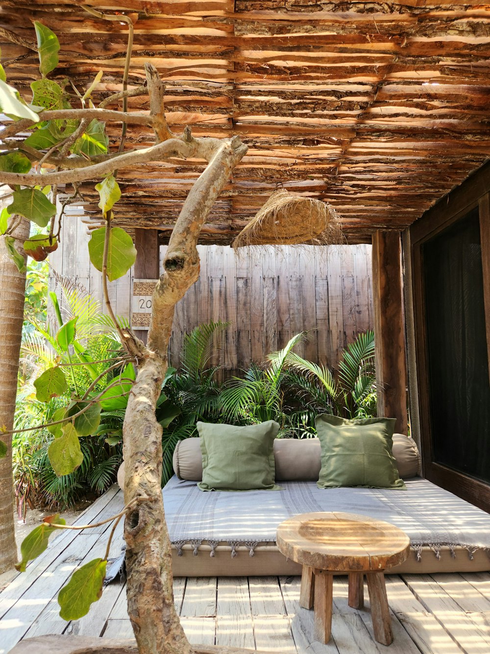 a wooden deck with a bench and a tree