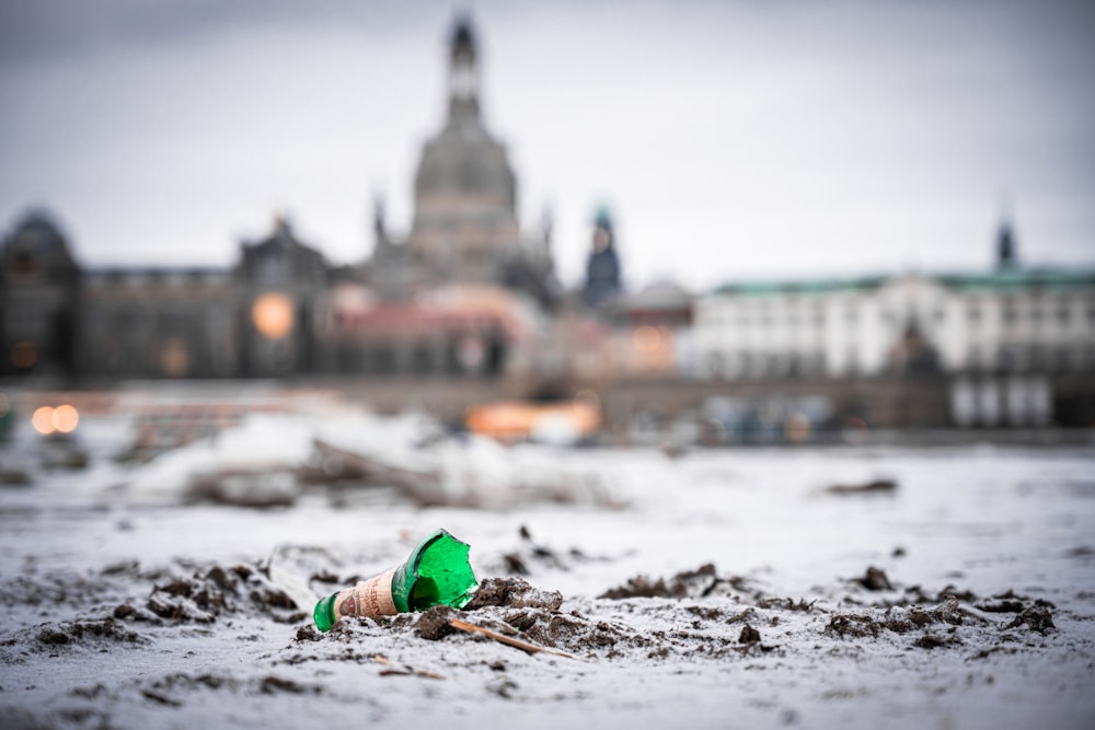 a green bottle sitting on top of a sandy beach