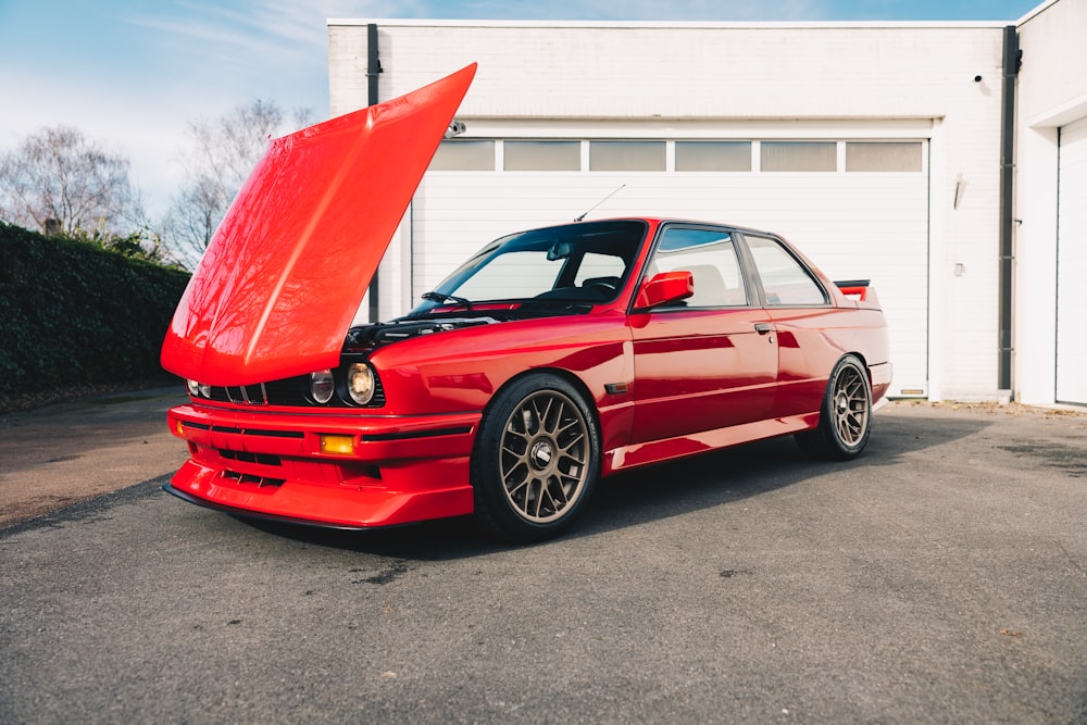 a red car parked in front of a garage