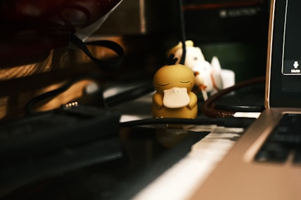 a small toy sitting on top of a desk next to a laptop