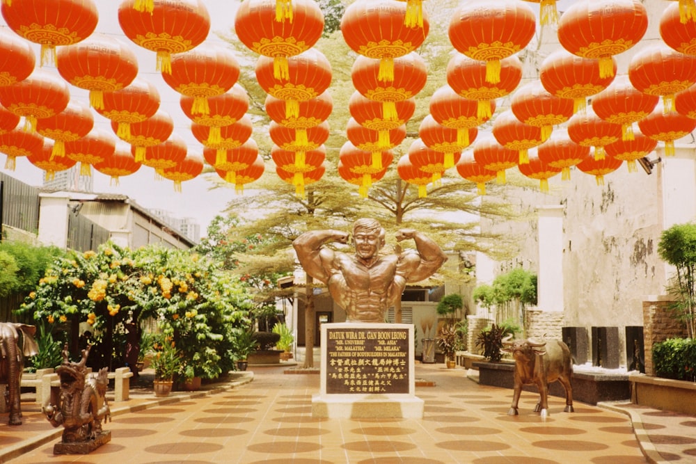a statue of a man surrounded by orange lanterns