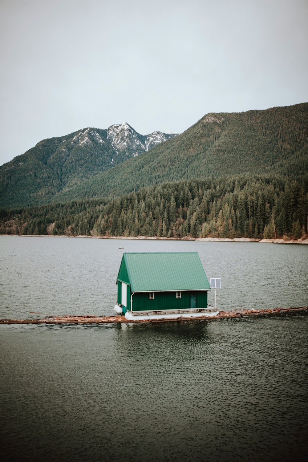 uma casa verde sentada em cima de um corpo de água