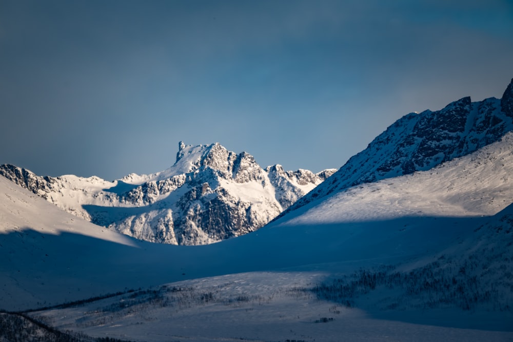 a mountain range covered in snow under a blue sky