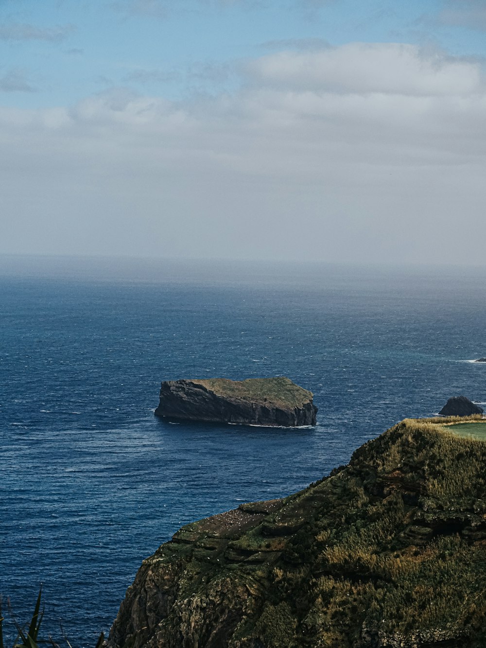 a large body of water sitting next to a lush green hillside