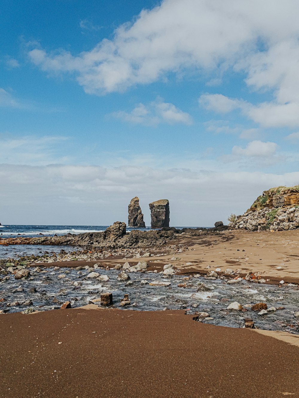 un paio di rocce sedute in cima a una spiaggia sabbiosa