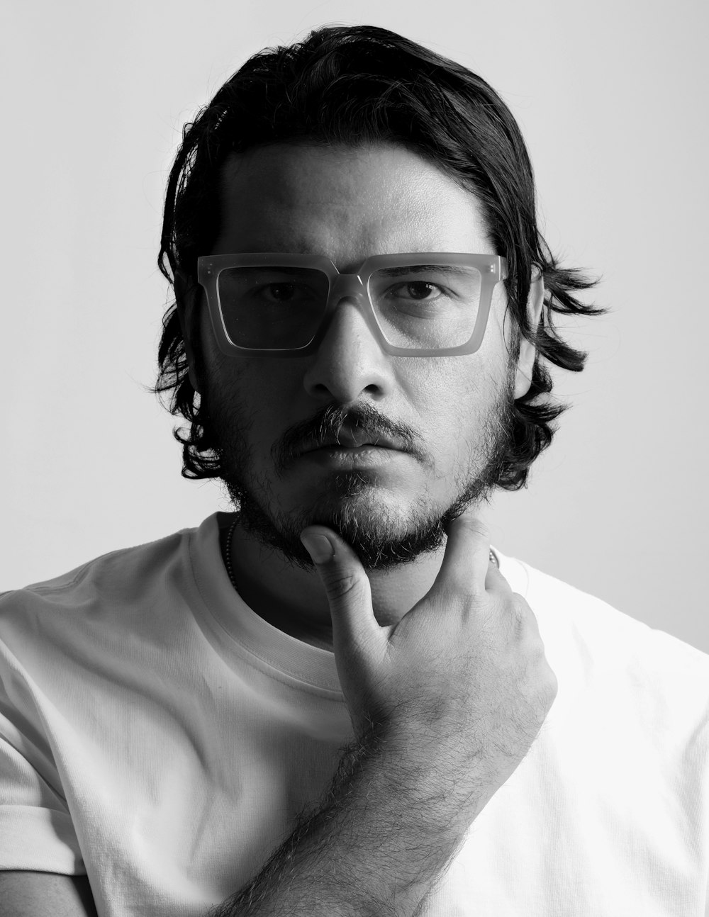 un homme avec une barbe et des lunettes posant pour une photo