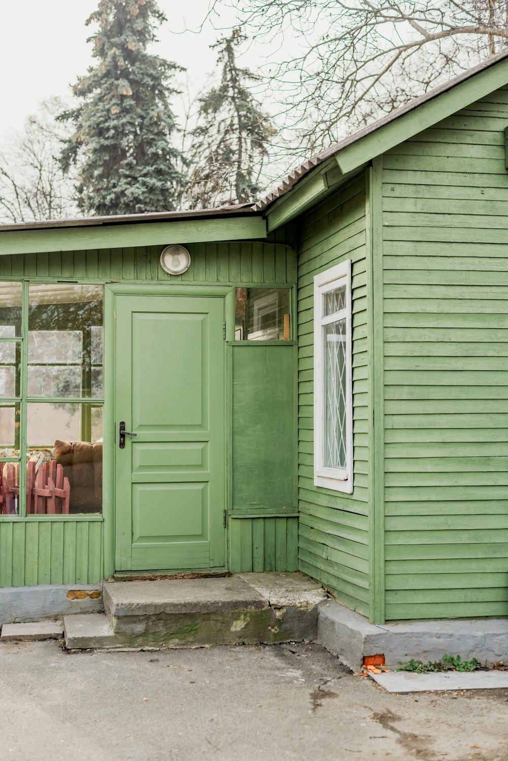 a green house with a clock on the front of it