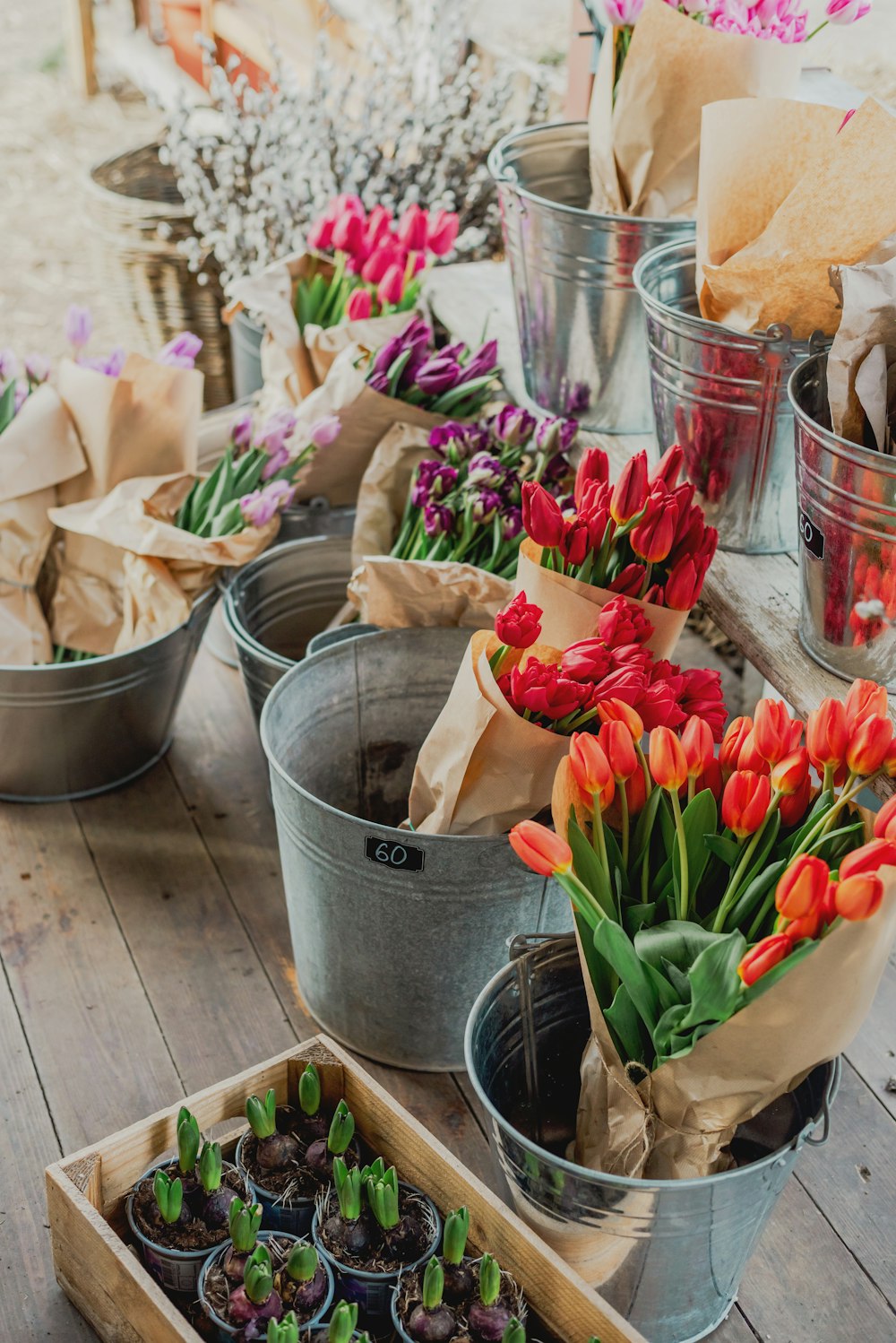 a wooden table topped with buckets filled with flowers