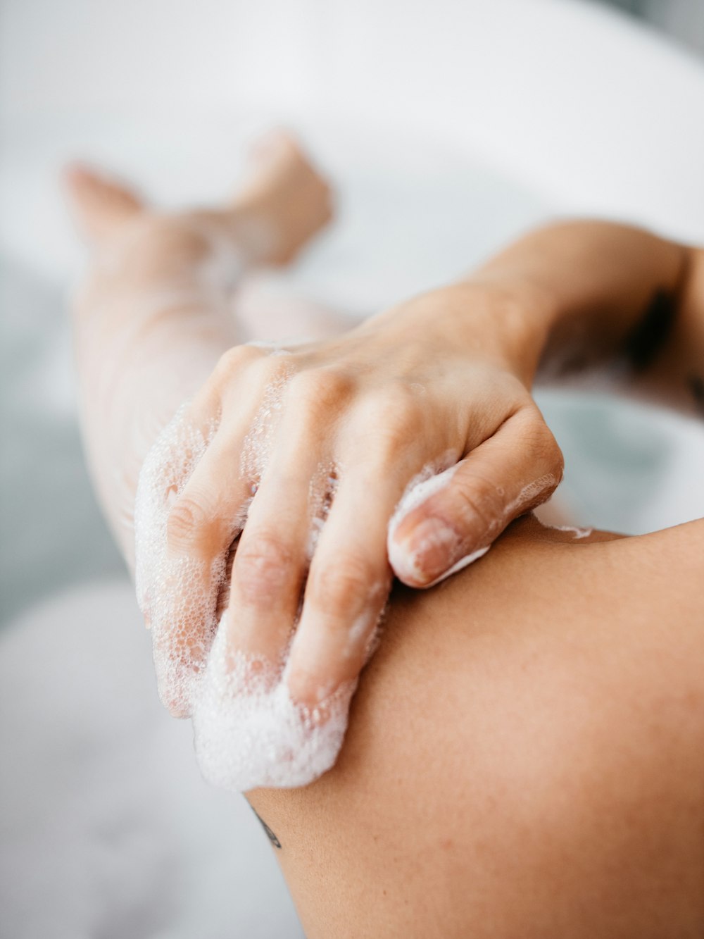 a person washing their arm with soap in a bathtub