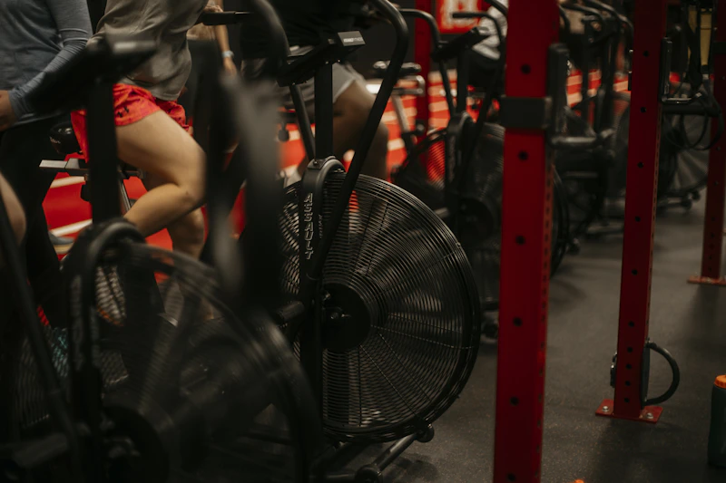 Riders in a dark RPM studio lit by neon during a spin class