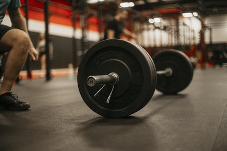 a man squatting down next to a barbell in a gym