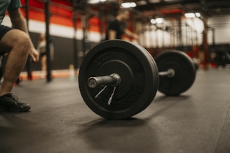a man squatting down next to a barbell in a gym