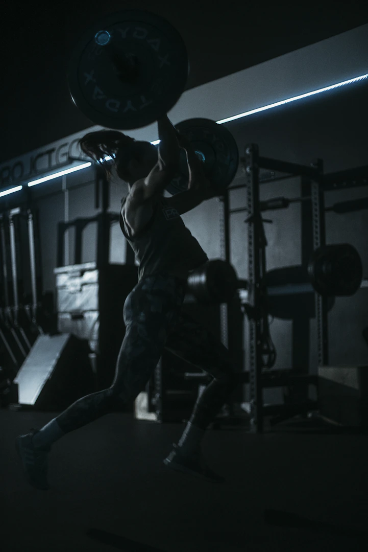 Athlete lifting barbell in a dark, intense gym — Athletic Edge Goa