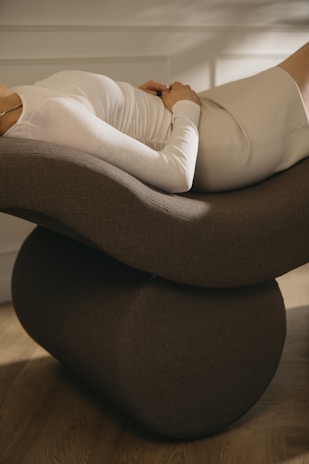 a woman laying on top of a chair on a hard wood floor