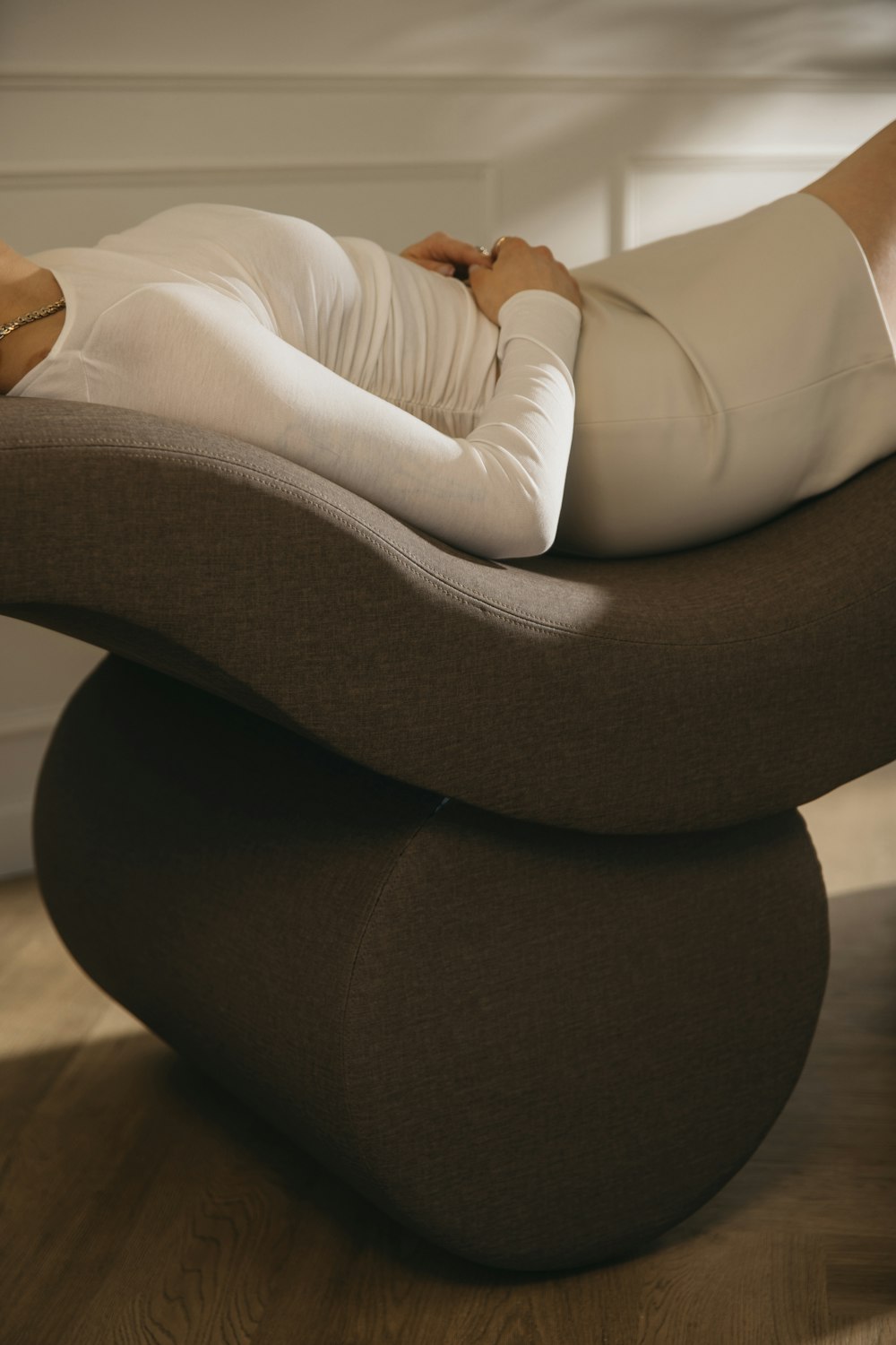 a woman laying on top of a chair on a hard wood floor