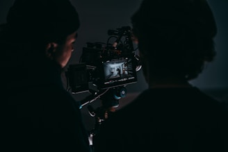 a man standing next to a woman in front of a camera