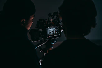 a man standing next to a woman in front of a camera