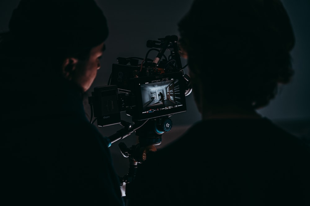 a man standing next to a woman in front of a camera